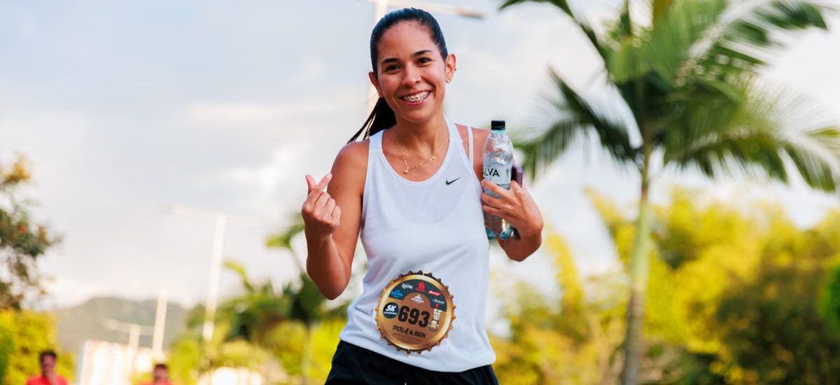 Smiling woman running a marathon outdoors in warm weather.