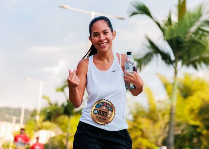 Smiling woman running a marathon outdoors in warm weather.